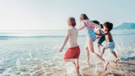Barn som løper ut i sjøen hånd i hånd