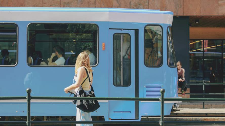 Jente i skjørt og singlet som står foran trikk i Oslo
