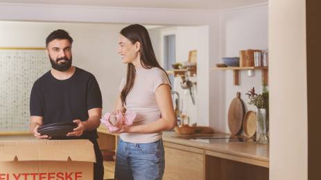 Ung mann og dame pakker ut servise på kjøkkenet