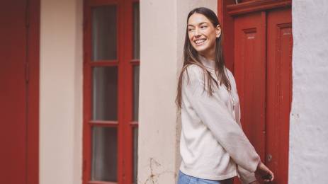 Ung kvinne smiler og låser seg inn en rød inngangsdør