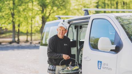 Smilende mann ved en arbeidsbil