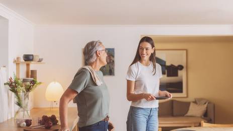 Voksen og ung kvinne smiler og dekker bord på kjøkkenet