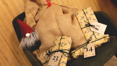Pakker fra KLPs julekalender plassert på en stol sammen med en nissebamse og striesekk