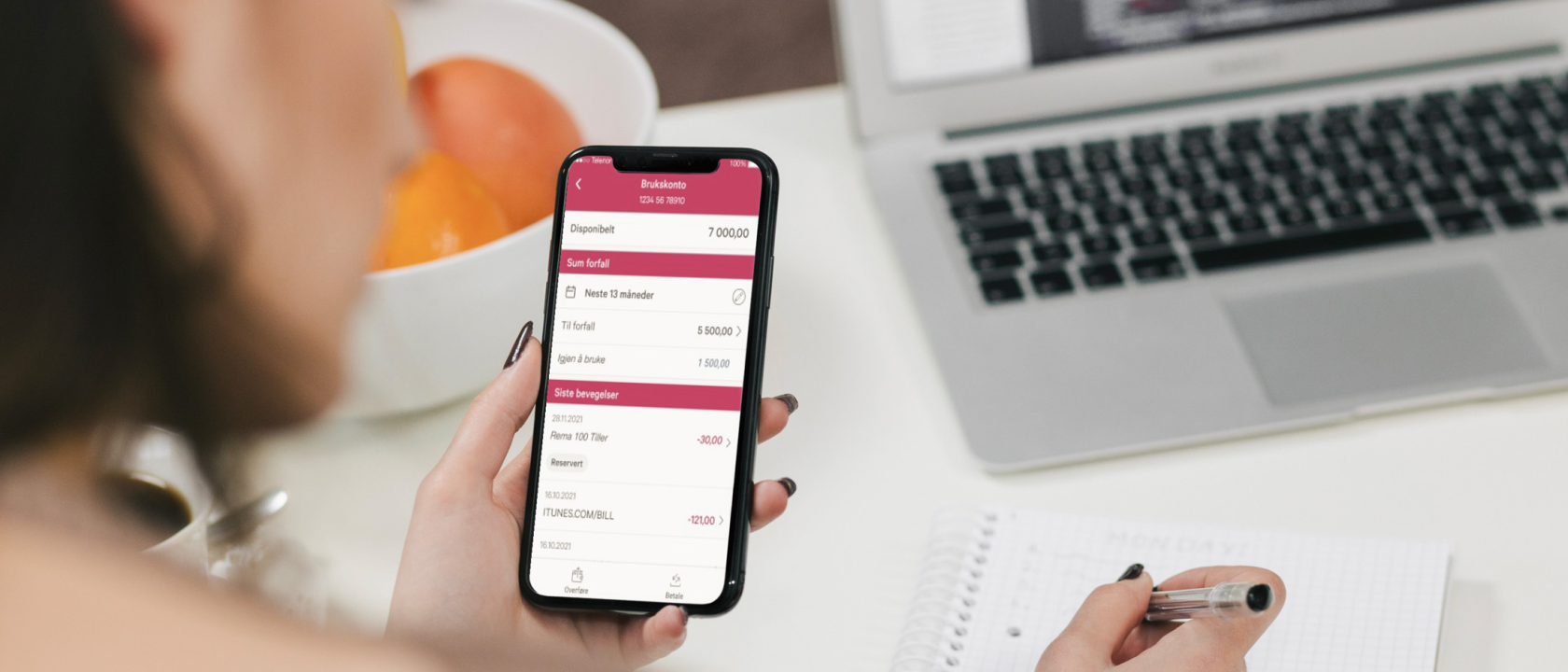Person sitter ved skrivebord og noterer i kladdebok fra mobilbanken