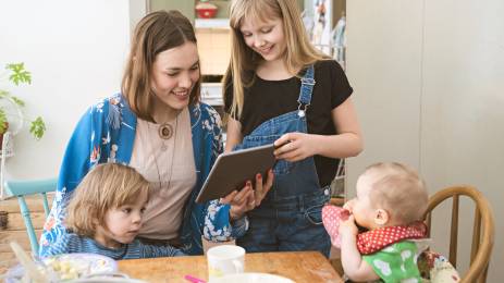Mor og tre barn som sitter rundt frokostbordet