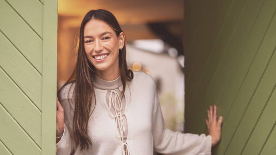 Ung kvinen står i døråpning og smiler