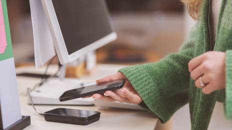Kvinne betaler med mobilen i butikkterminal