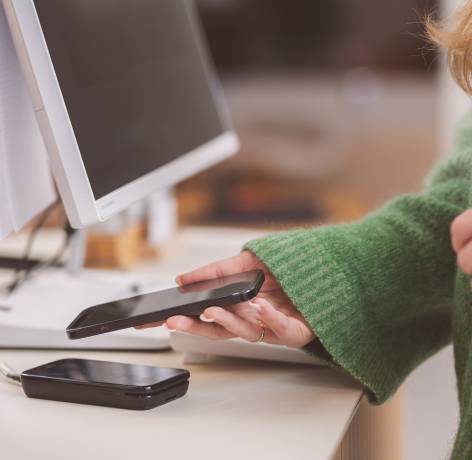 Kvinne betaler med mobilen i butikkterminal