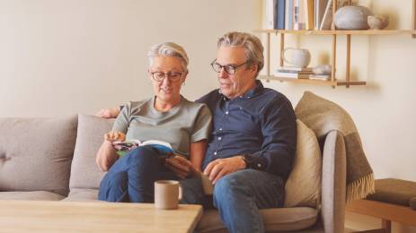 Voksent par i sofa ser i en bok sammen