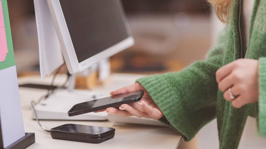 Kvinne betaler med mobilen i butikkterminal