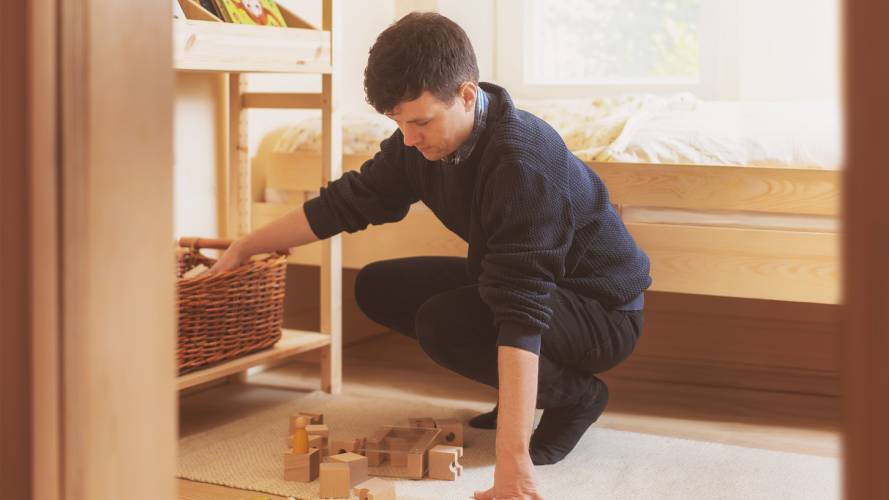 Ung mann rydder leker på barnerom