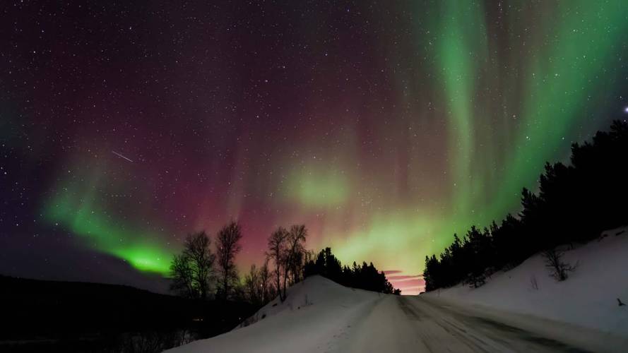 Nordlys over vintervei opp på fjellet