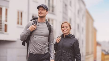 Ungt smilende par i treningstøy på gate med bygårder i bakgrunnen