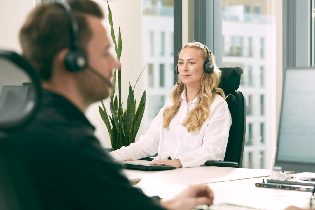 Ung dame som jobber sitter ved pult med headset