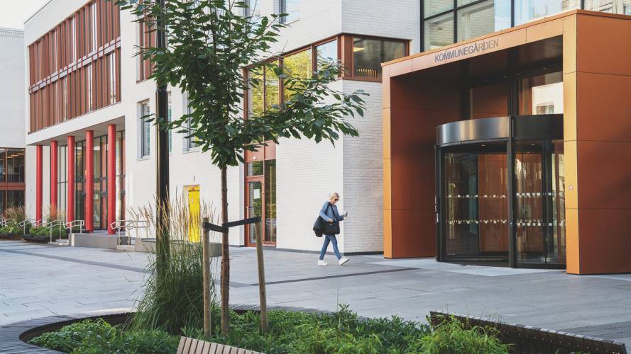 Dame som går forbi inngangspartiet til et kommunehus