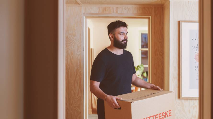 Ung mann bærer flytteske innendørs