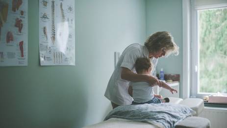 Sykepleier hjelper lite barn på behandlingsrom på sykehuset