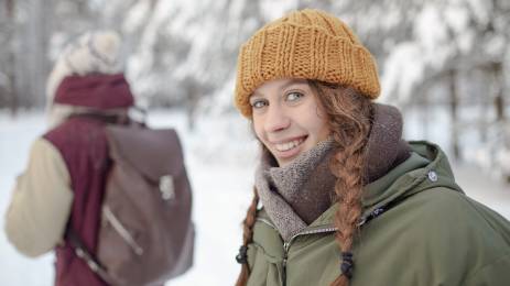 Jente med gul lue på tur som smiler