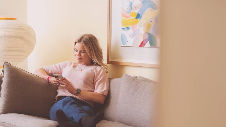 Kvinne i sofa med mobil i hånden