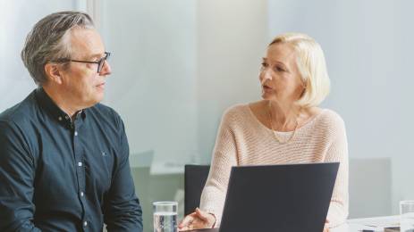 Mann og dame som sitter på et kontor og diskuterer