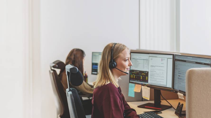 Dame som jobber på kundesenter som sitter med headset foran en skjerm