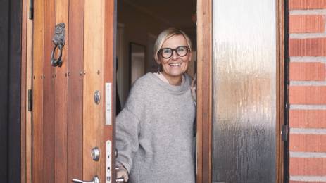 Smilende dame med briller i døråpning