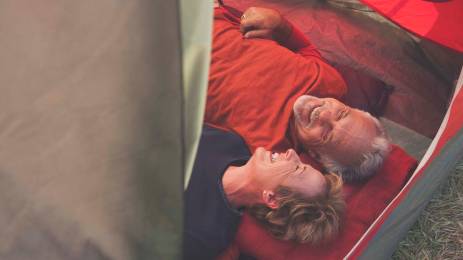 Senior Caucasian couple relaxing in tent
