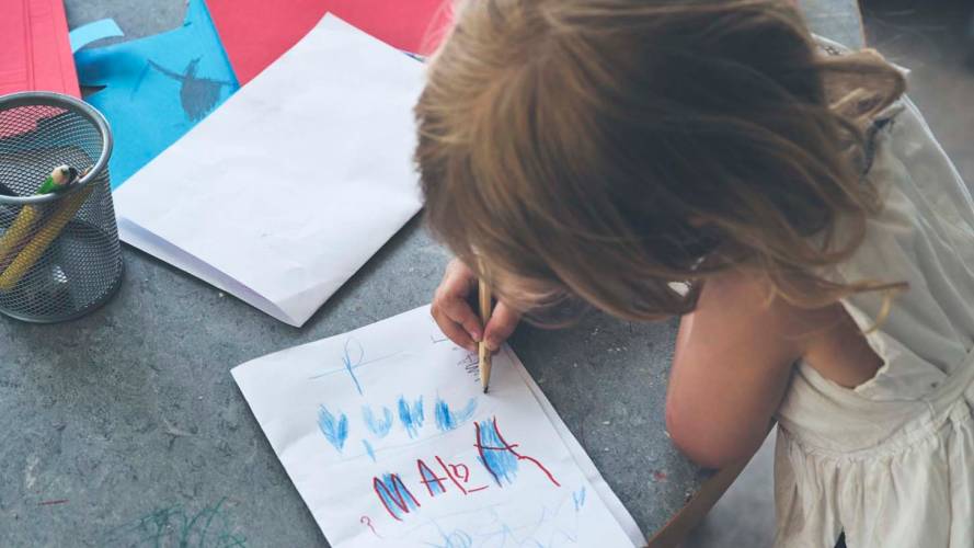 Liten jente tegner tegning i barnehagen