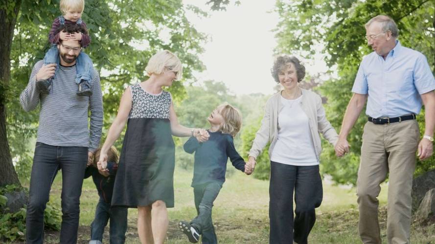 Familiebilde av tre generasjoner som holder hendene til hverandre