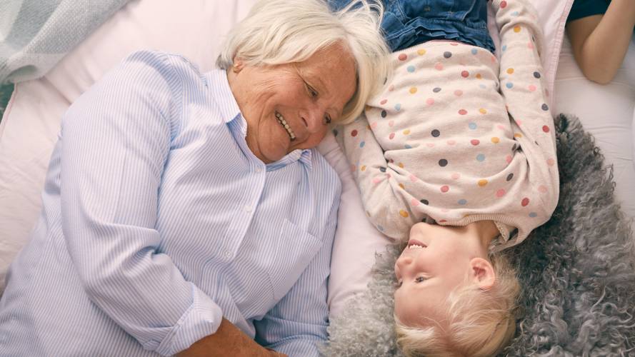 Bestemor ligger på gulvet med sitt barnebarn.