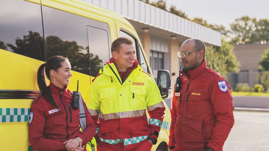 Ambulansearbeidere som står foran en ambulanse