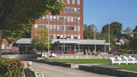 Dame som sitter på en benk foran kommunehuset