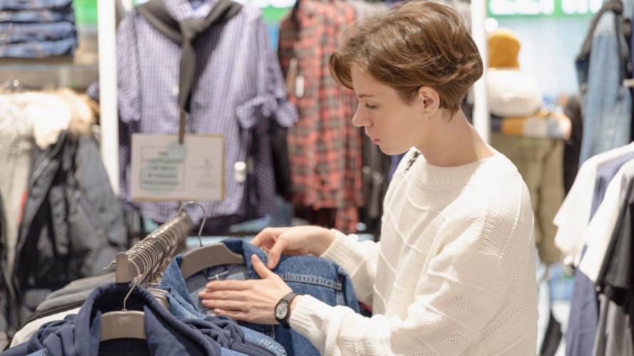 Dame som ser på en jeansjakke i en klesbutikk