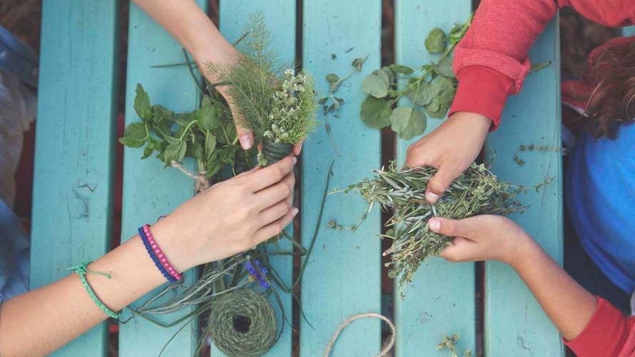 To jentehender som fletter blomster og lager dekorasjoner