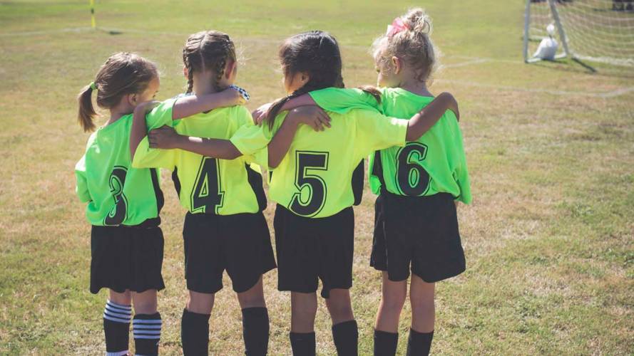 Fotballjenter holder rundt hverandre i god lagånd