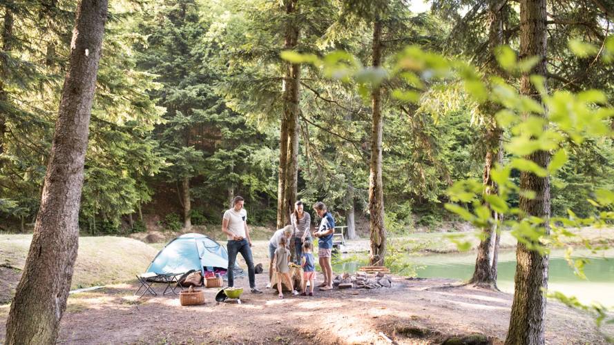 Familie som telter ved en innsjø i skogen